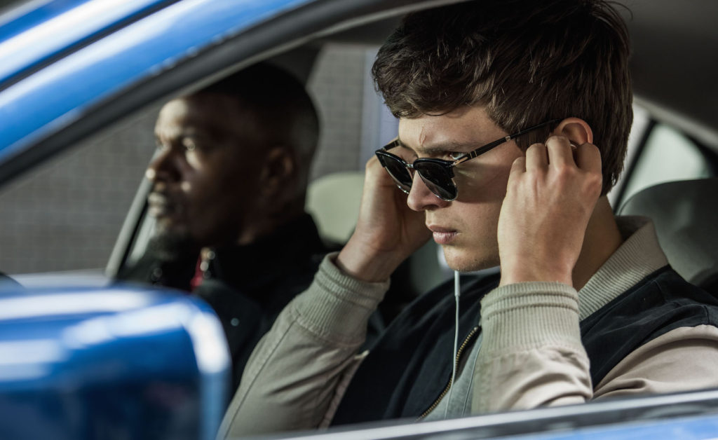 Baby (ANSEL ELGORT) and Bats (JAMIE FOXX) on the way to the post office job with Buddy (JON HAMM) and Darling (EIZA GONZALEZ) as cops pull up next to them in TriStar Pictures' BABY DRIVER.